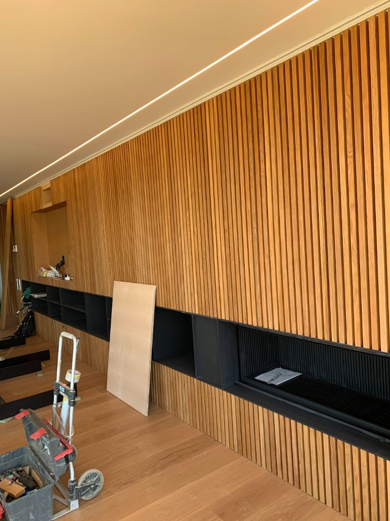 Madera ranurada - Pared con estanterías y chimenea